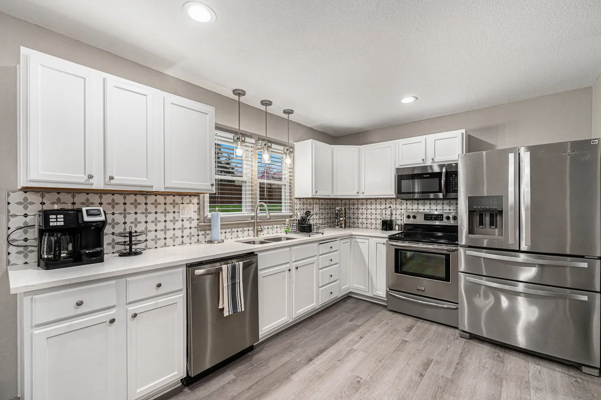 A bright, functional kitchen with stainless steel appliances, white cabinetry, and a stylish backsplash. Sunlight streams in through a window, illuminating ample workspace for meal preparation. The modern updates and spacious design highlight the kitchen's readiness for everything from everyday cooking to hosting family feasts.