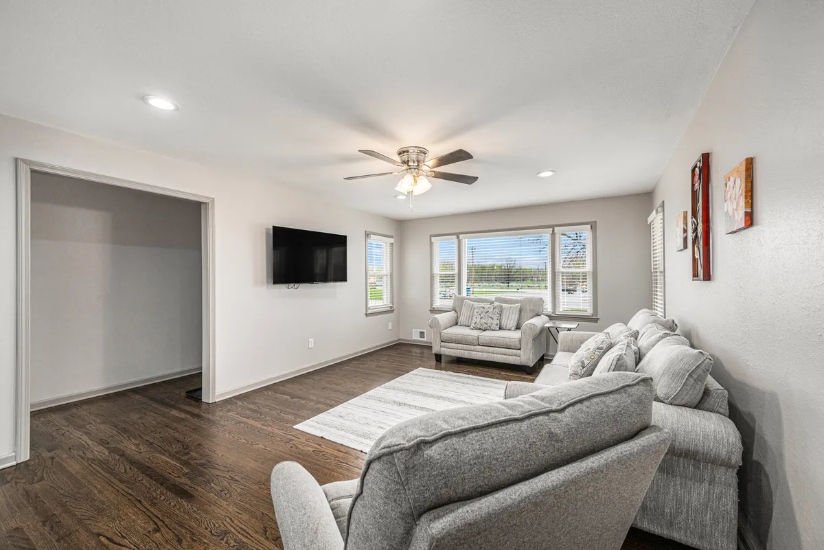 The image showcases a cozy living area with plush, inviting couches arranged around a stylish coffee table, large windows that flood the room with natural light, and a television set for entertainment. The space feels warm and welcoming, perfect for relaxing, sharing stories, or enjoying scenic views outside.