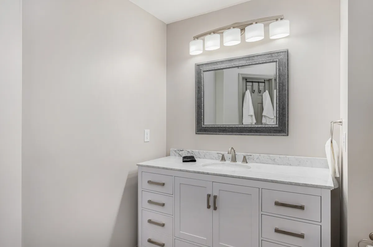 A recently remodeled bathroom featuring a modern vanity sink, large mirror, and sleek light fixture. The mood is calm and serene, inviting moments of self-care and relaxation.